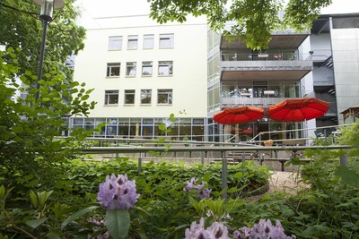 Blick aus dem Grünen auf die Terasse und Rückseite des Altenpflegeheims